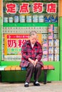 Elder woman having a nap in front of farmacy shop, Kunming, China